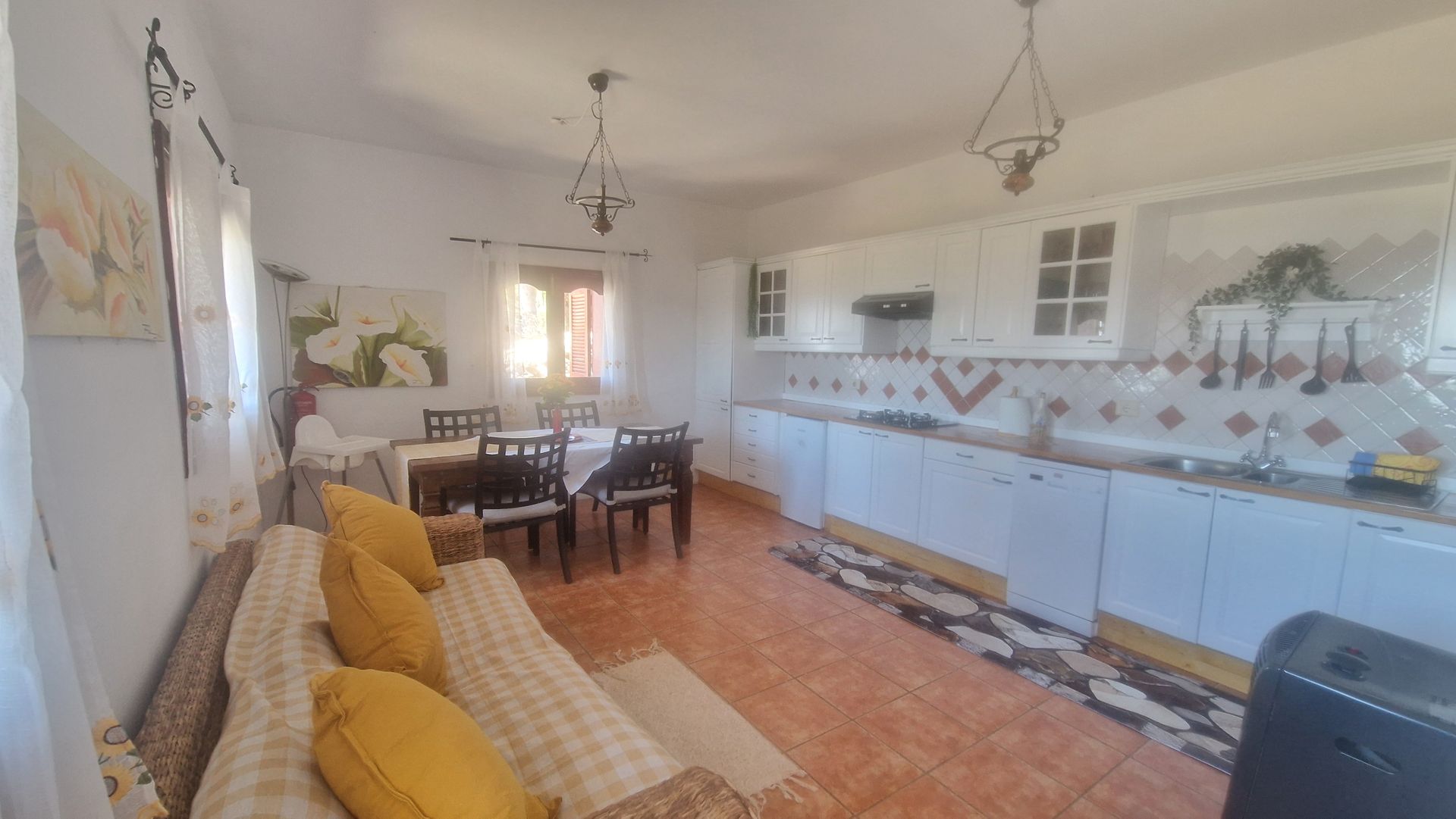A living room with a couch , table and chairs and a kitchen.