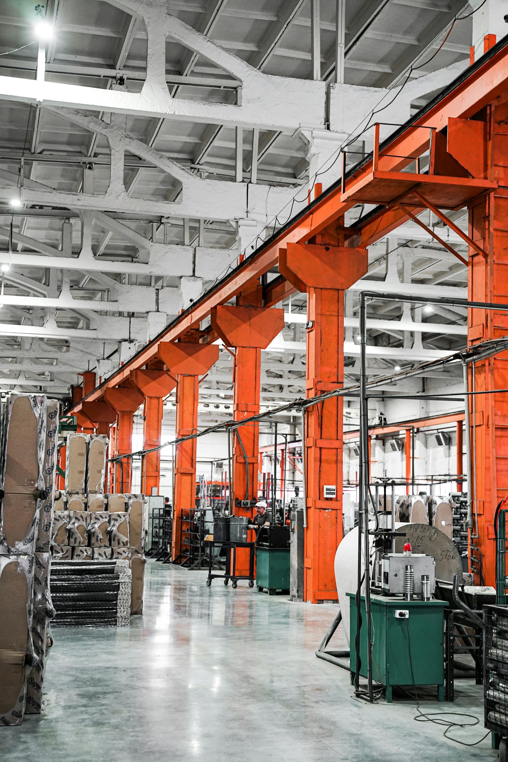 Orange industrial supports in a factory. Boxes and machines line the floor.