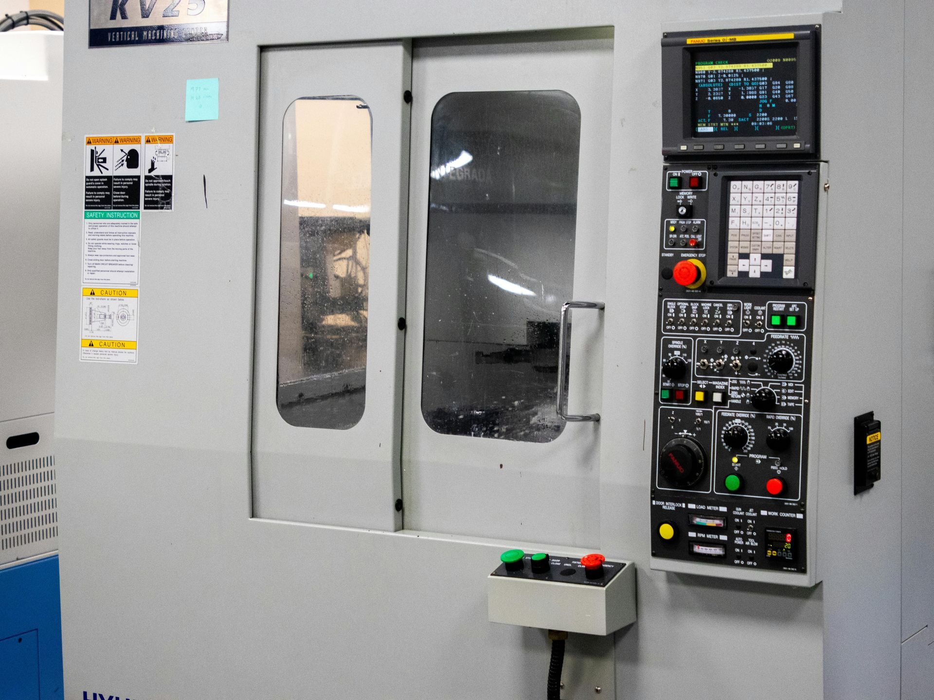 A grey CNC machine with a control panel, door, and monitor.