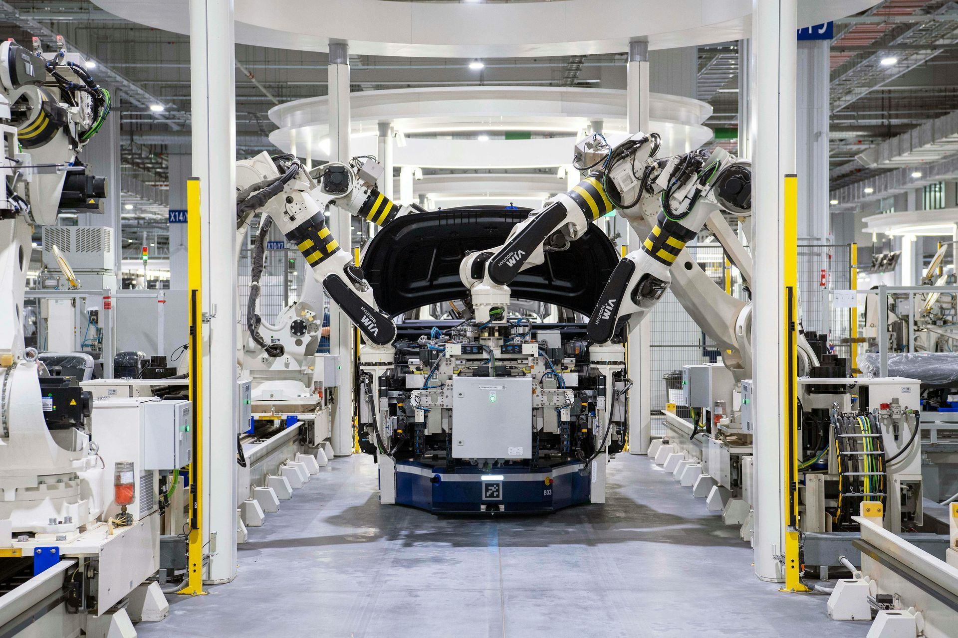 Robotic arms assembling a car body in a factory.