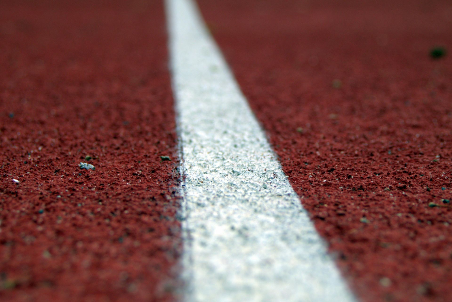 White painted line on a red running track, close-up.