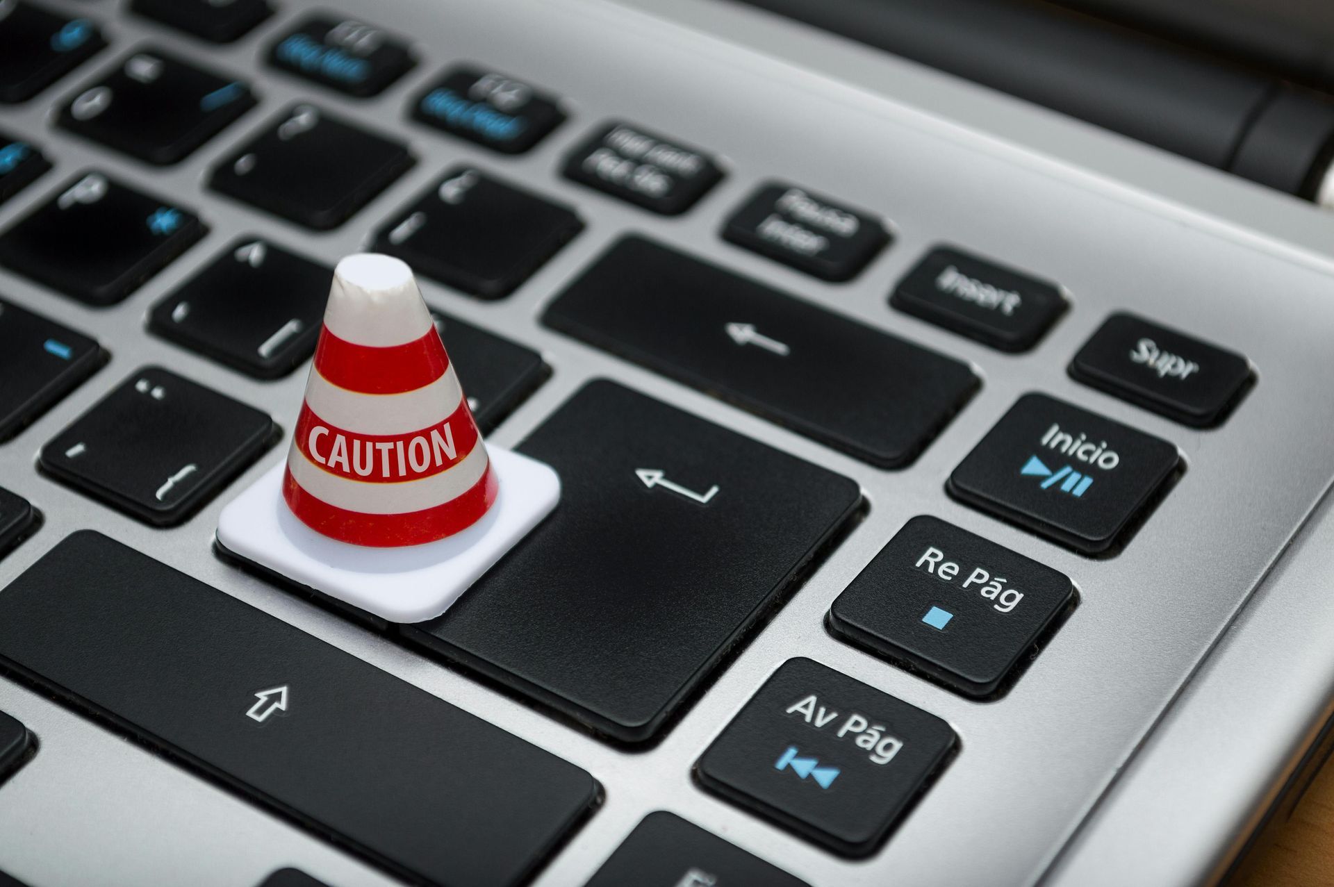 Caution cone on a laptop keyboard, highlighting the Enter key.
