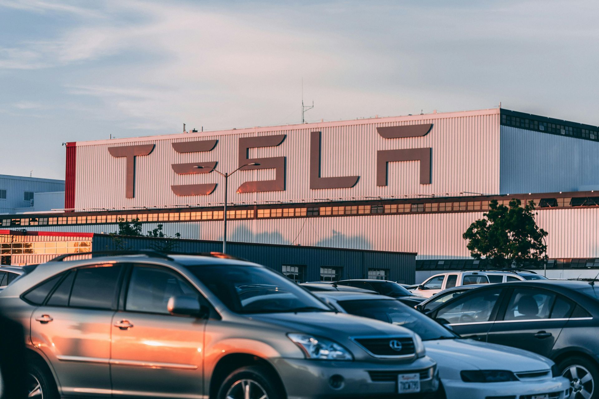 Tesla factory building with cars parked in front.