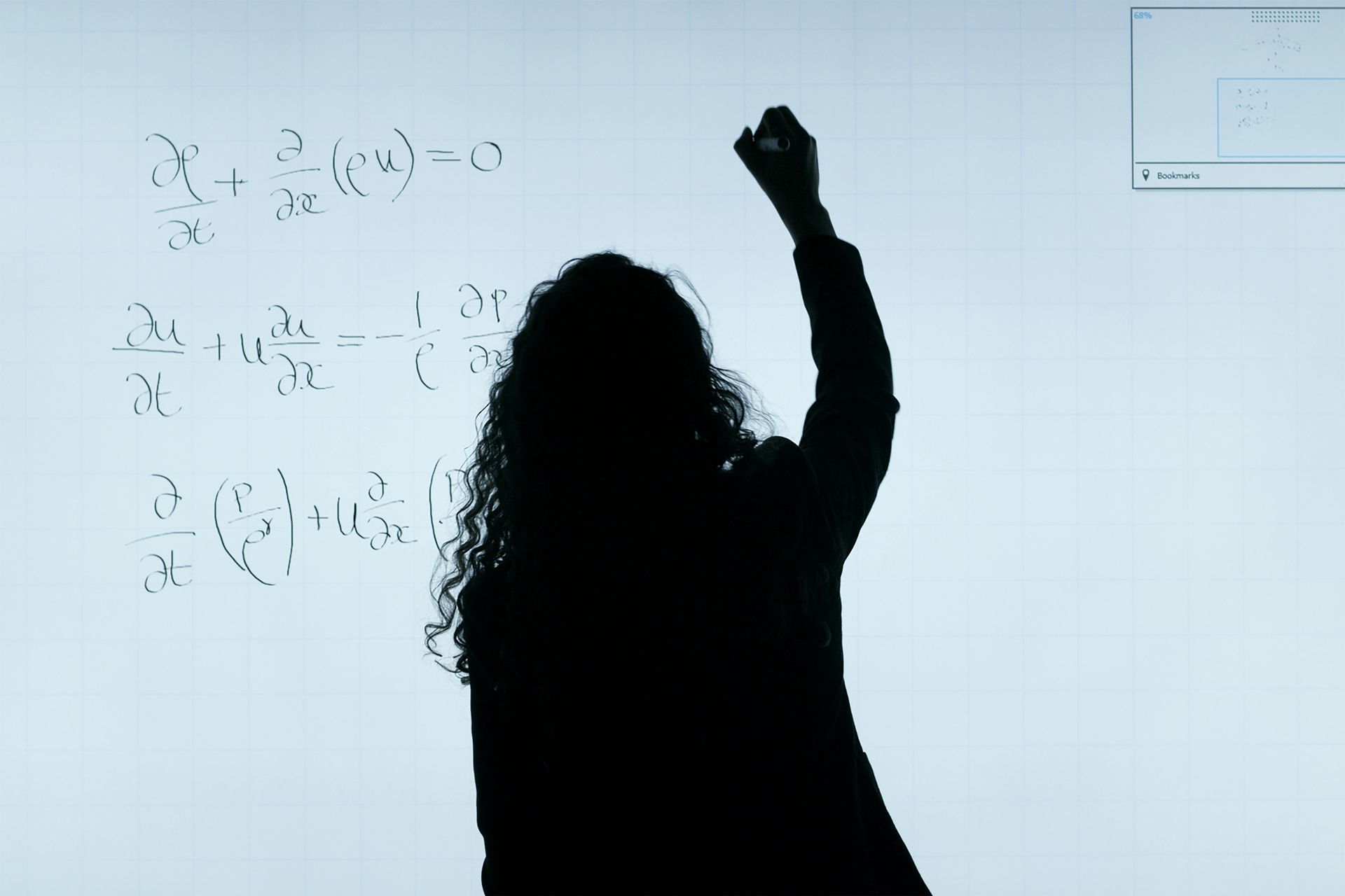 Silhouette of a person writing mathematical equations on a whiteboard.