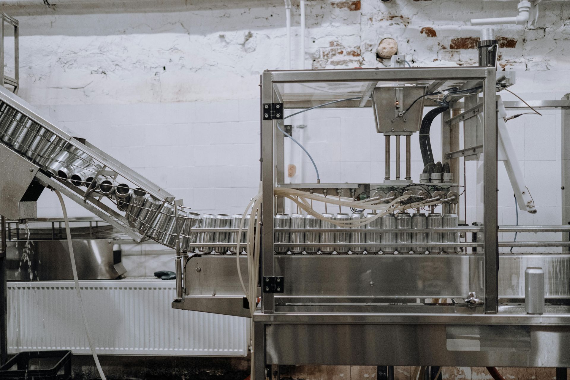 Aluminum cans on a conveyor belt being filled and sealed by automated machinery in a factory.