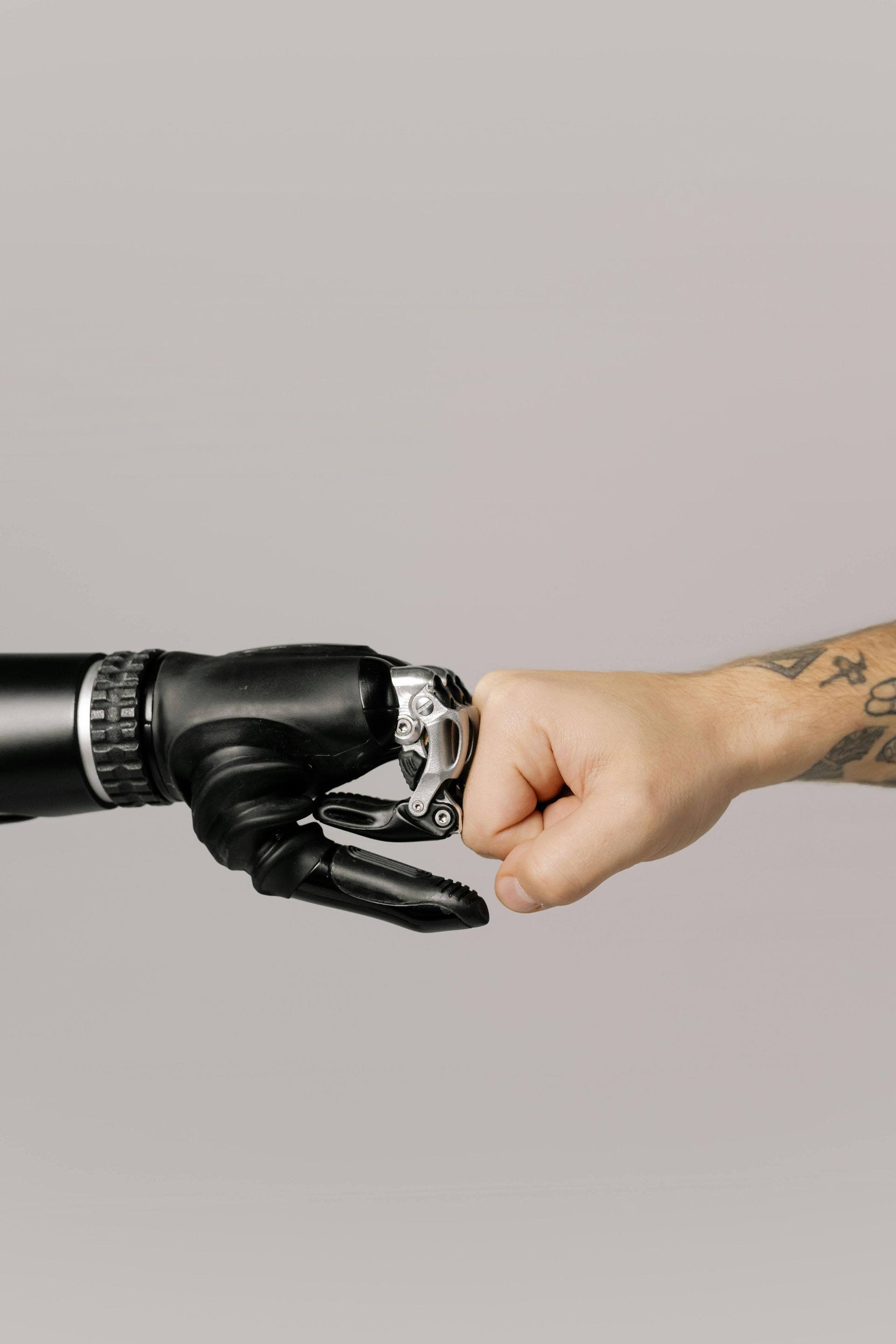 Black prosthetic fist bumping a human fist, tattoos visible.