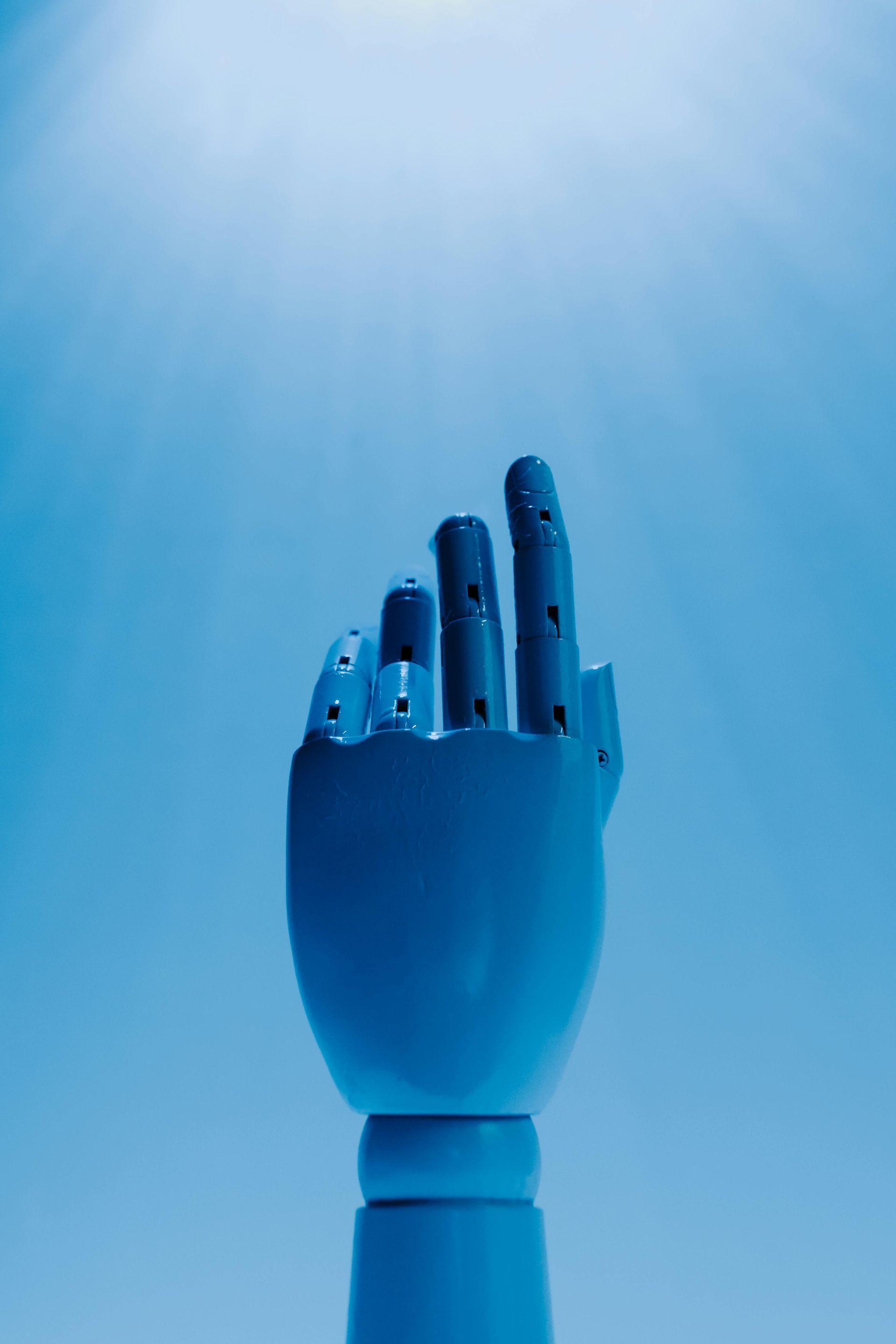 Blue prosthetic hand raised with two fingers extended.