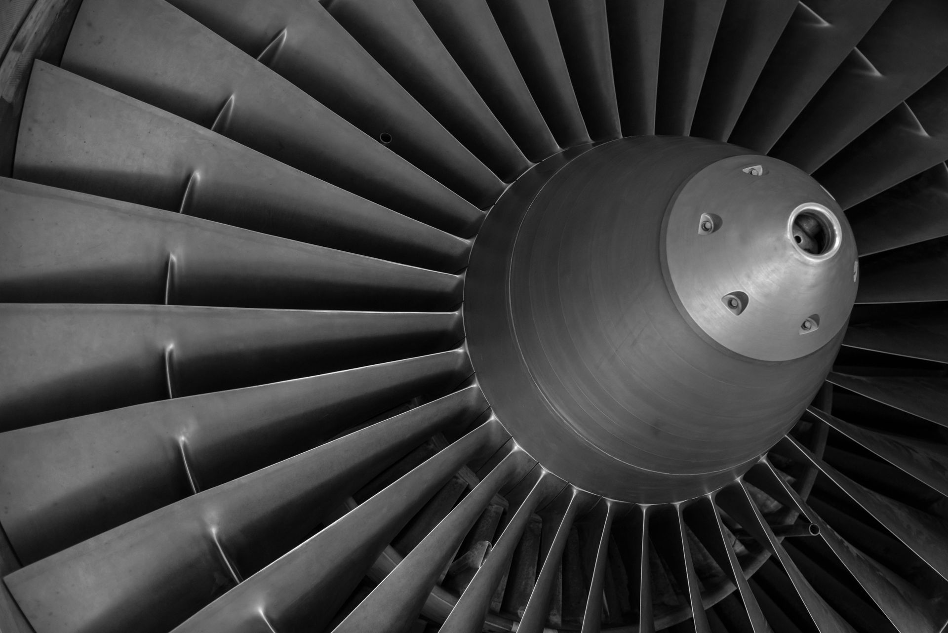 Close-up view of a jet engine's fan blades in grayscale.