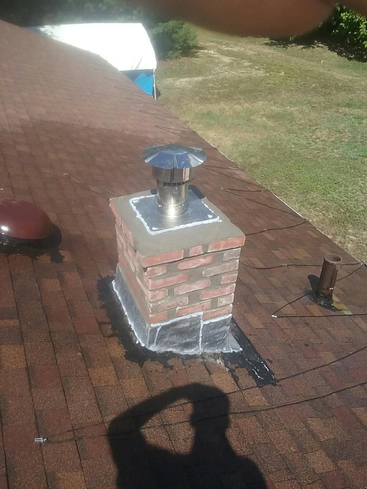 A brick chimney is sitting on top of a brick roof.