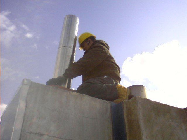 A man wearing a hard hat is working on a chimney