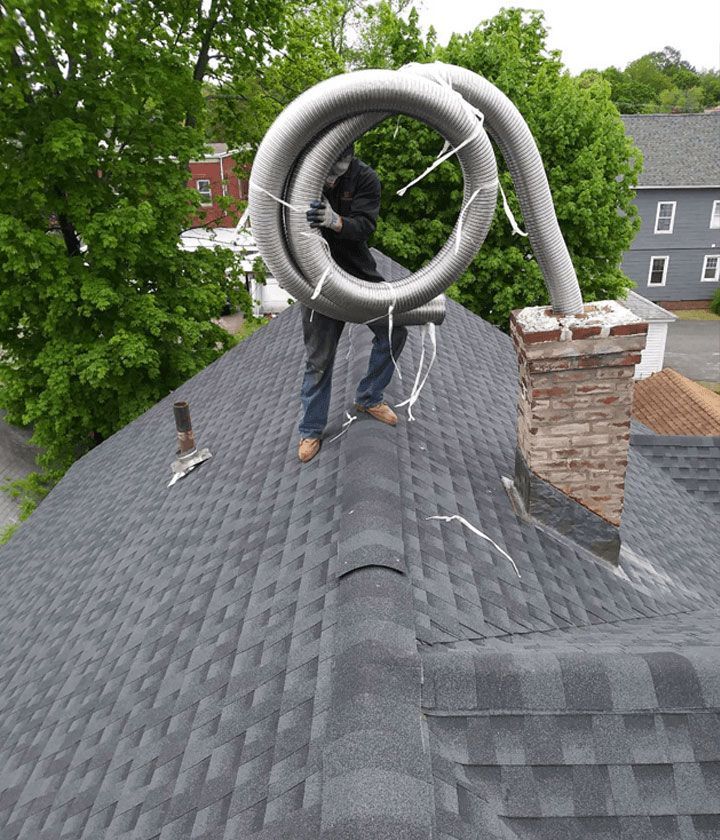 A man is standing on top of a roof holding a pipe