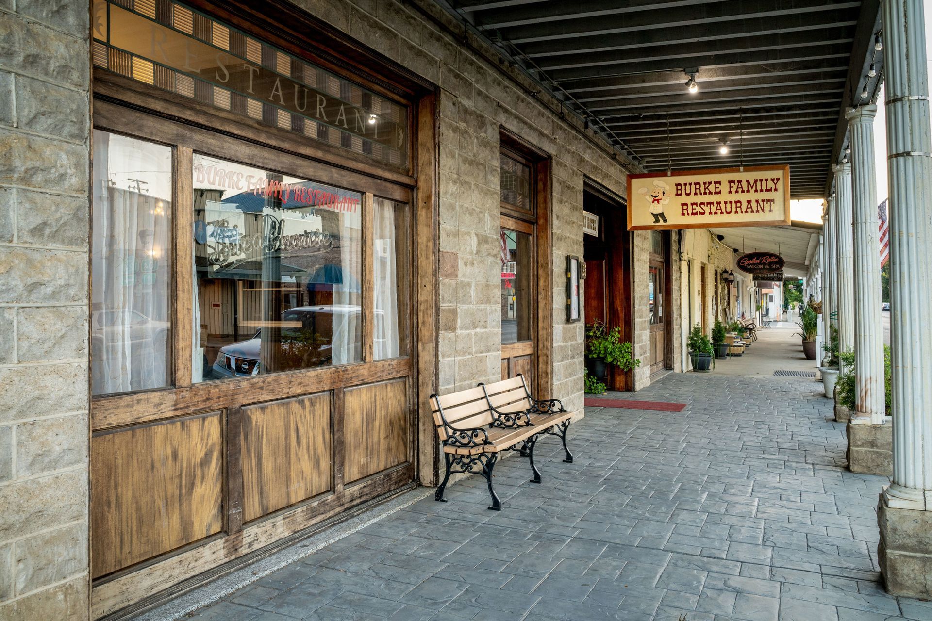 A wooden bench is sitting in front of a building.
