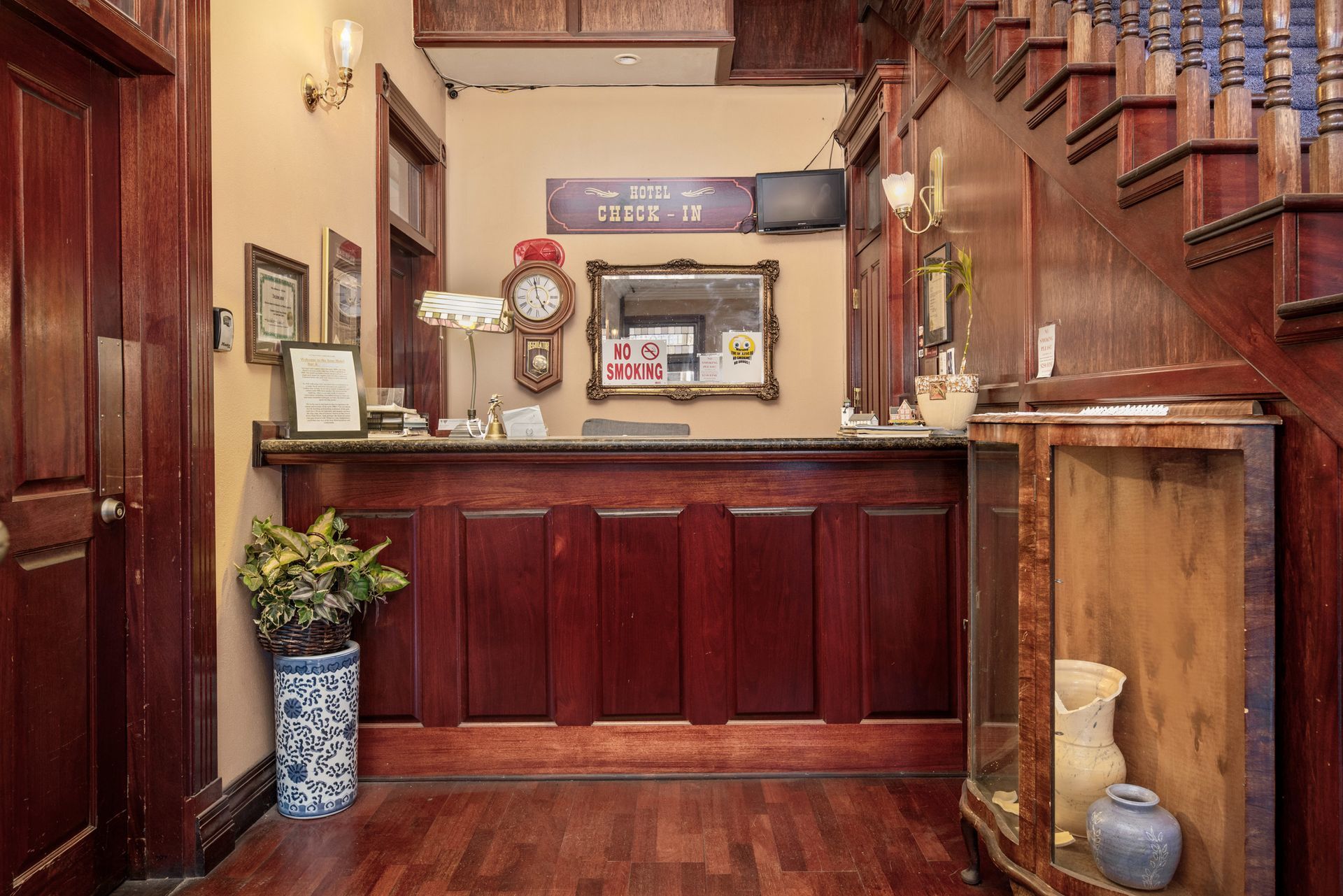 A hotel lobby with a wooden counter and a clock on the wall.