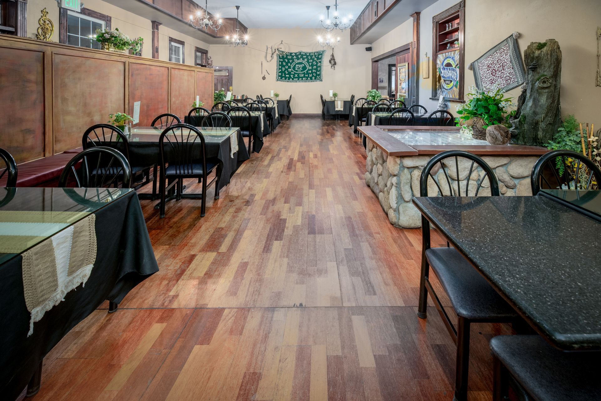 A long dining room with wooden floors and tables and chairs.