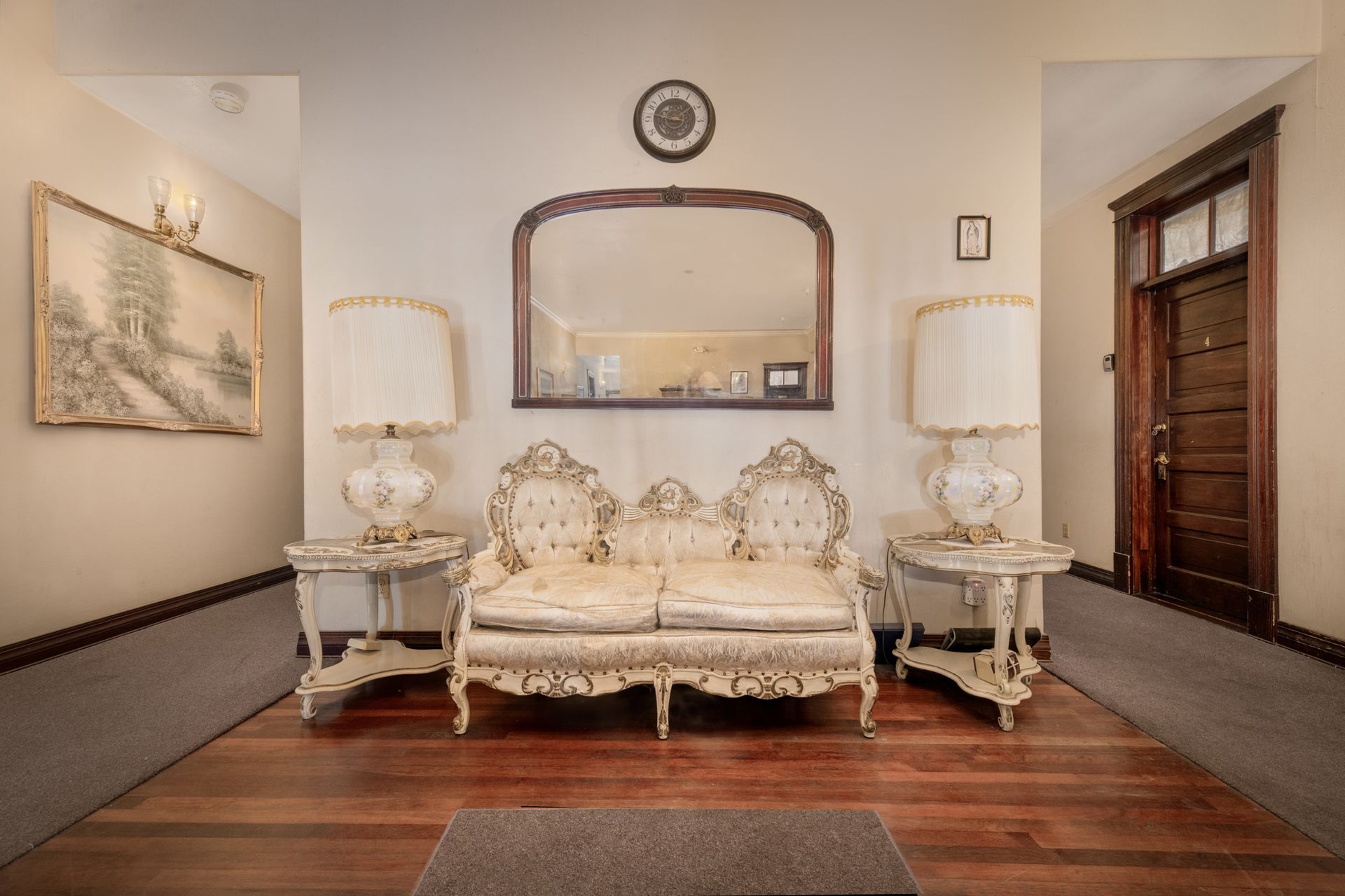 A living room with a couch , lamps , and a mirror.