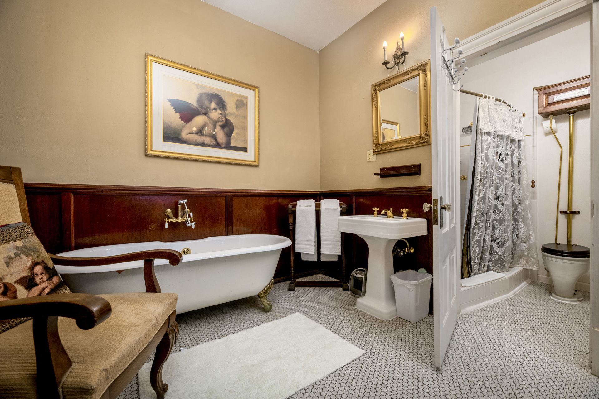 A bathroom with a bathtub , sink , toilet and chair.