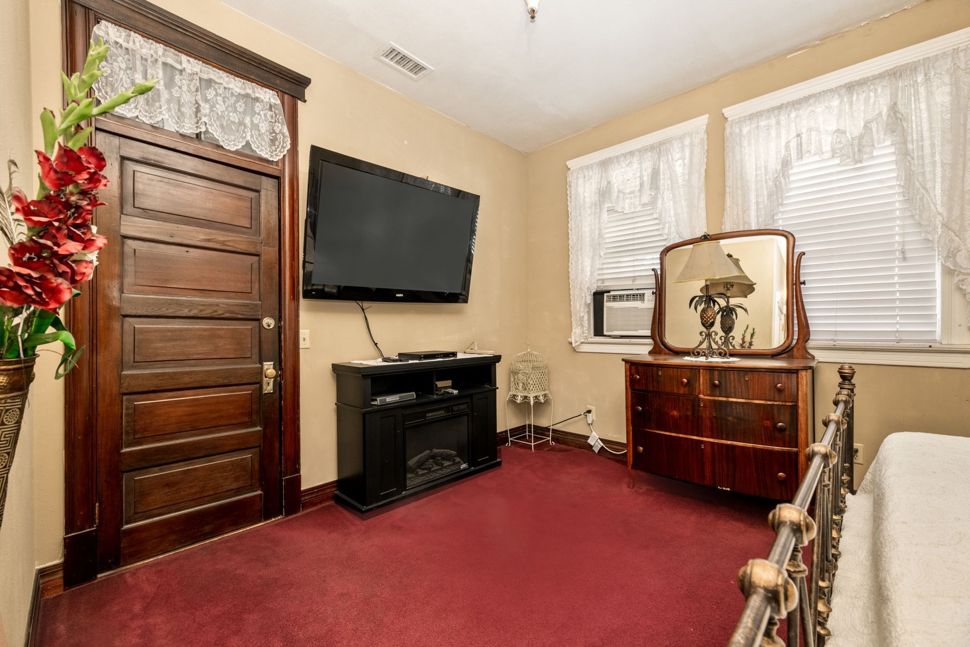 A bedroom with a bed , dresser , television , and mirror.