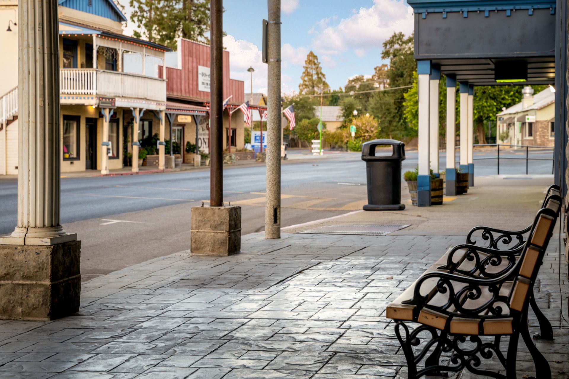 A bench is sitting on the sidewalk in front of a building in a small town.