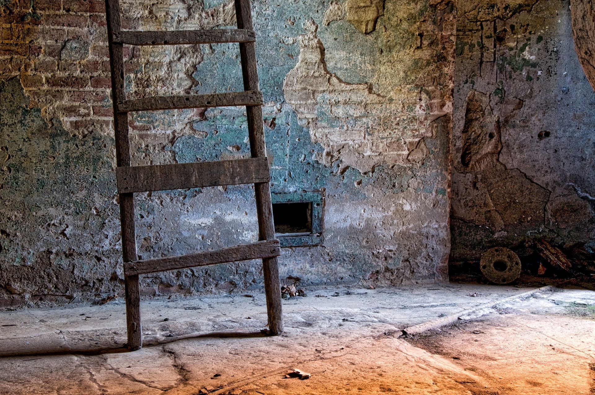 A wooden ladder is leaning against a brick wall in a room.