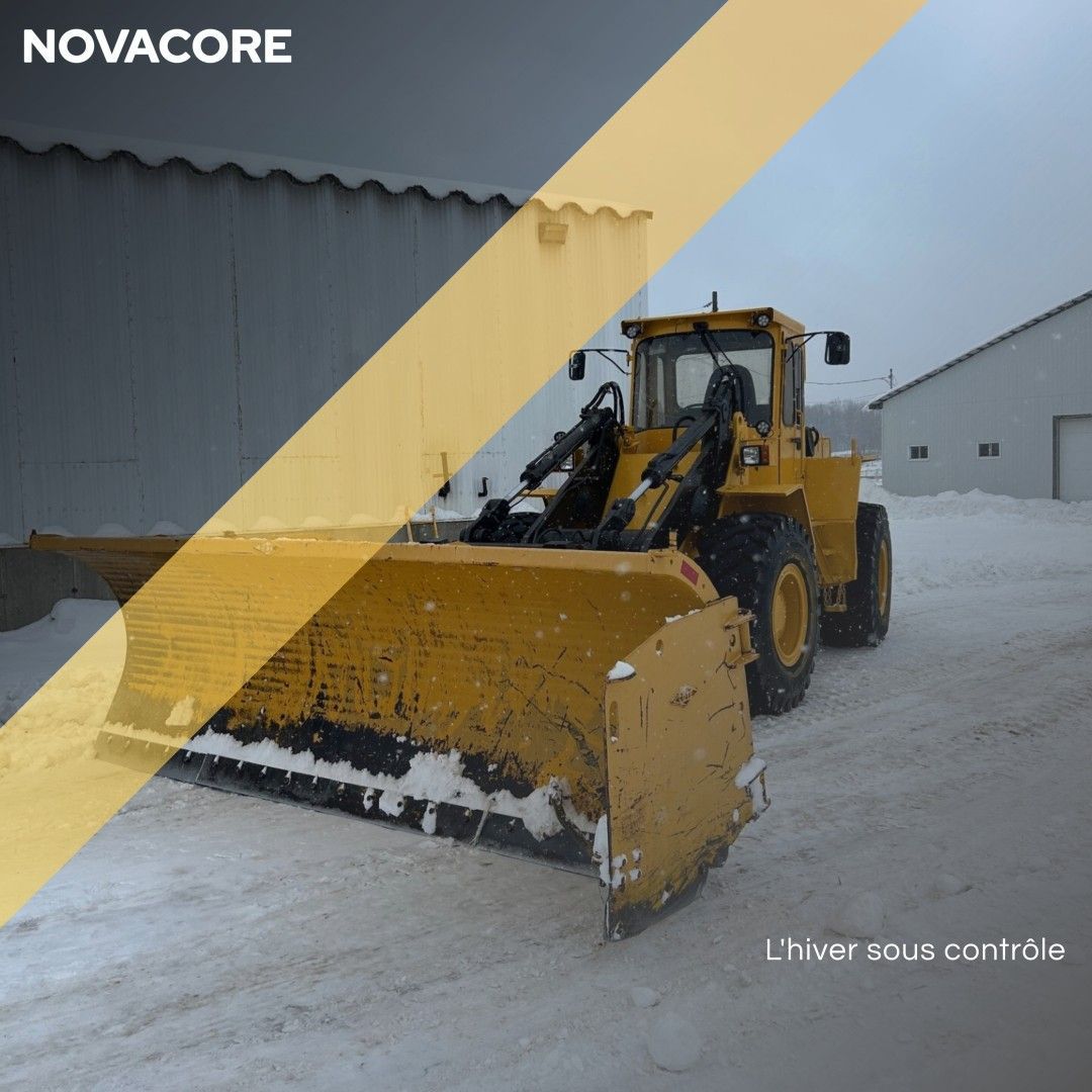 Un tracteur jaune est garé dans la neige avec novacore écrit en dessous