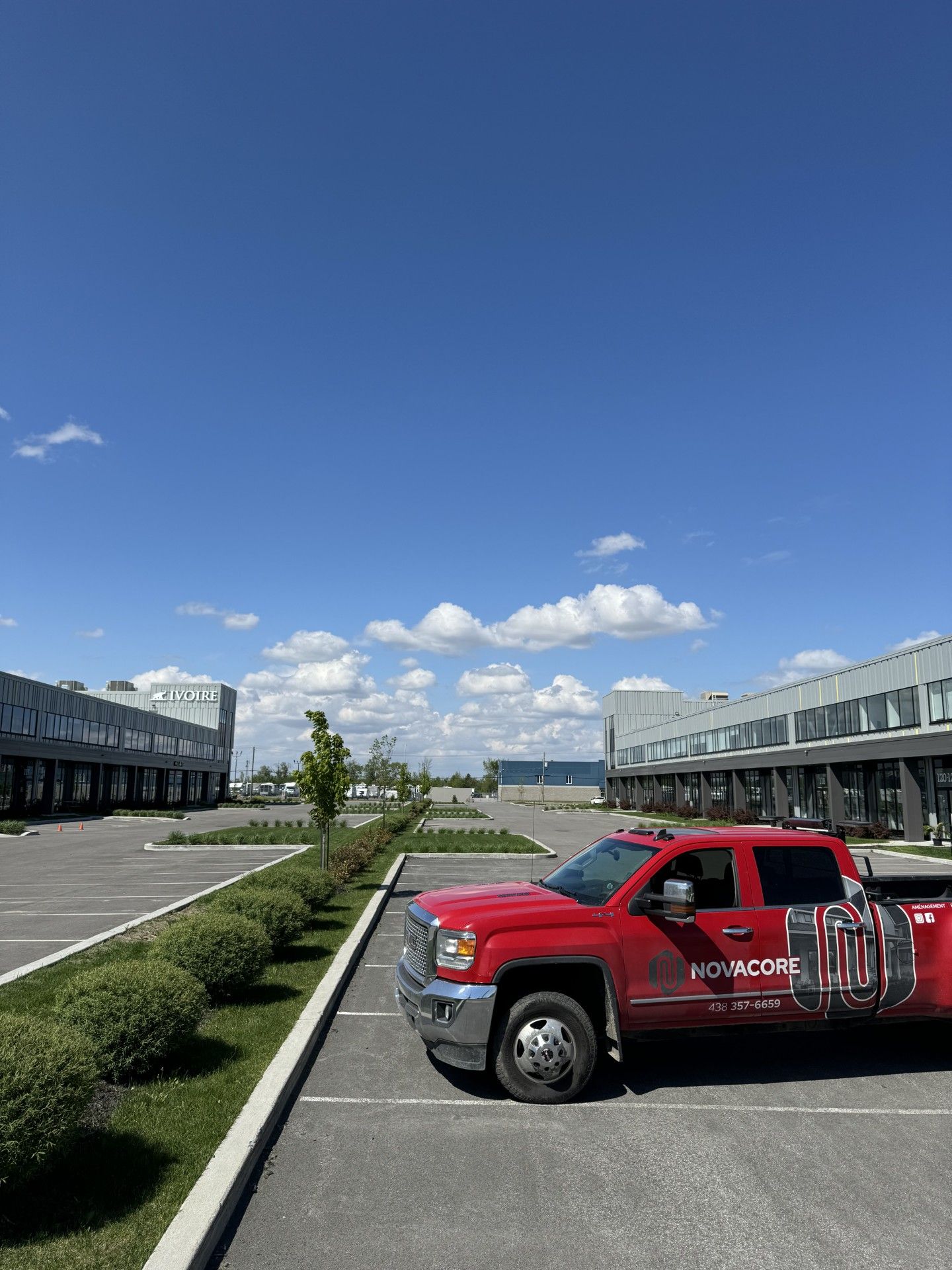 Un camion rouge est garé sur un parking devant un immeuble.