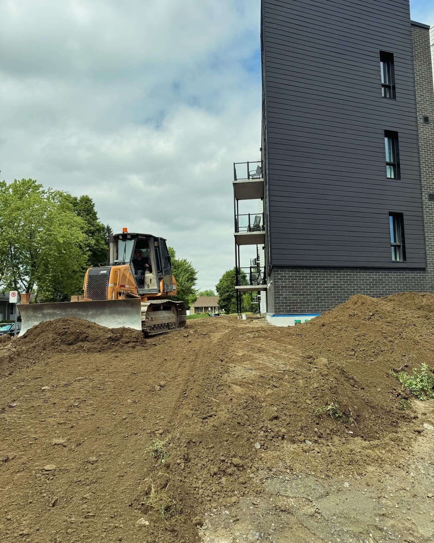 Un bulldozer déplace de la terre devant un bâtiment.