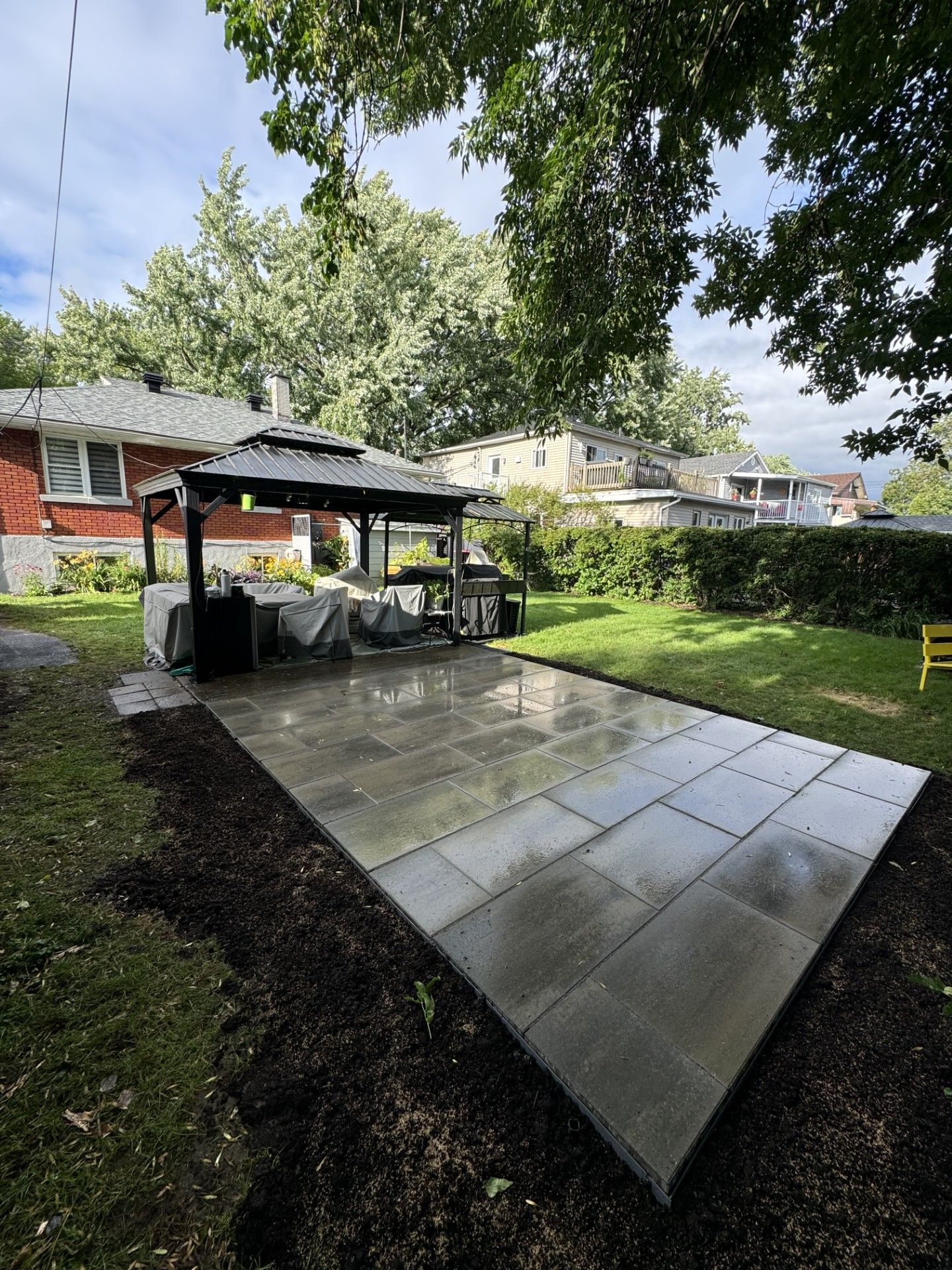 Un patio avec un gazebo dans l'arrière-cour d'une maison.