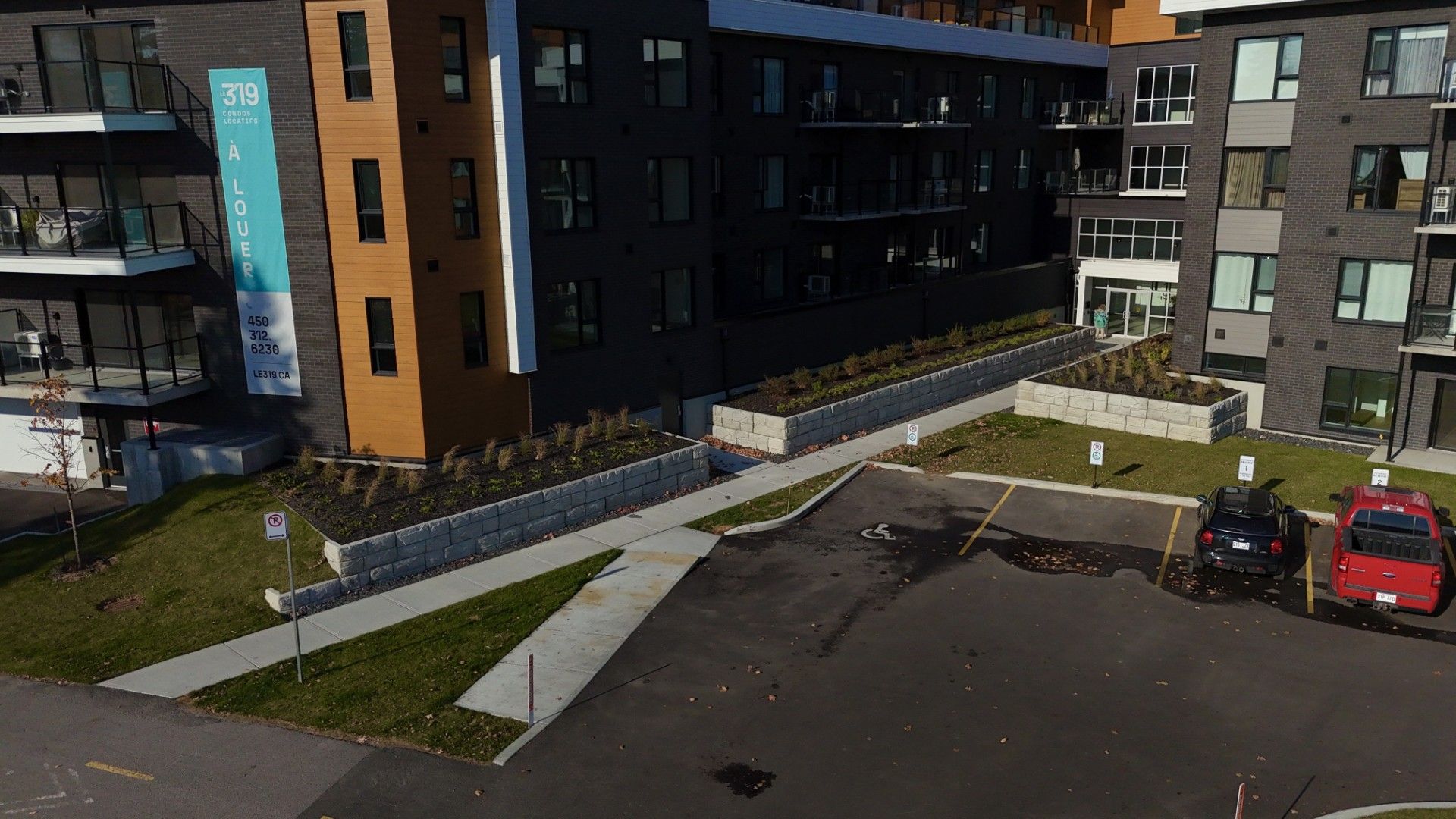 Une vue aérienne d'un parking devant un grand immeuble d'appartements.