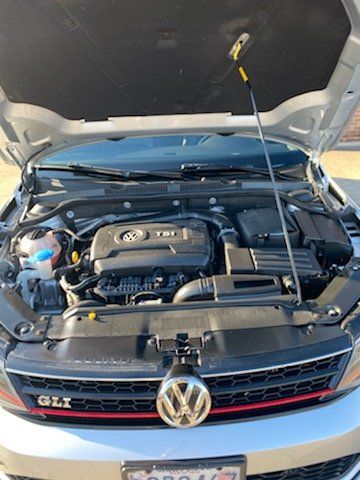 The hood of a silver volkswagen jetta with the hood open.
