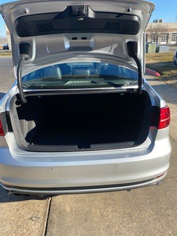 The trunk of a silver car is open and empty.