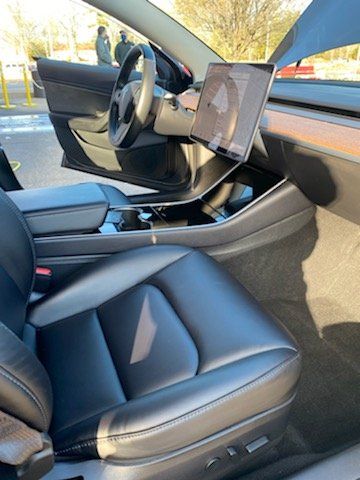 The interior of a tesla model 3 with the door open.