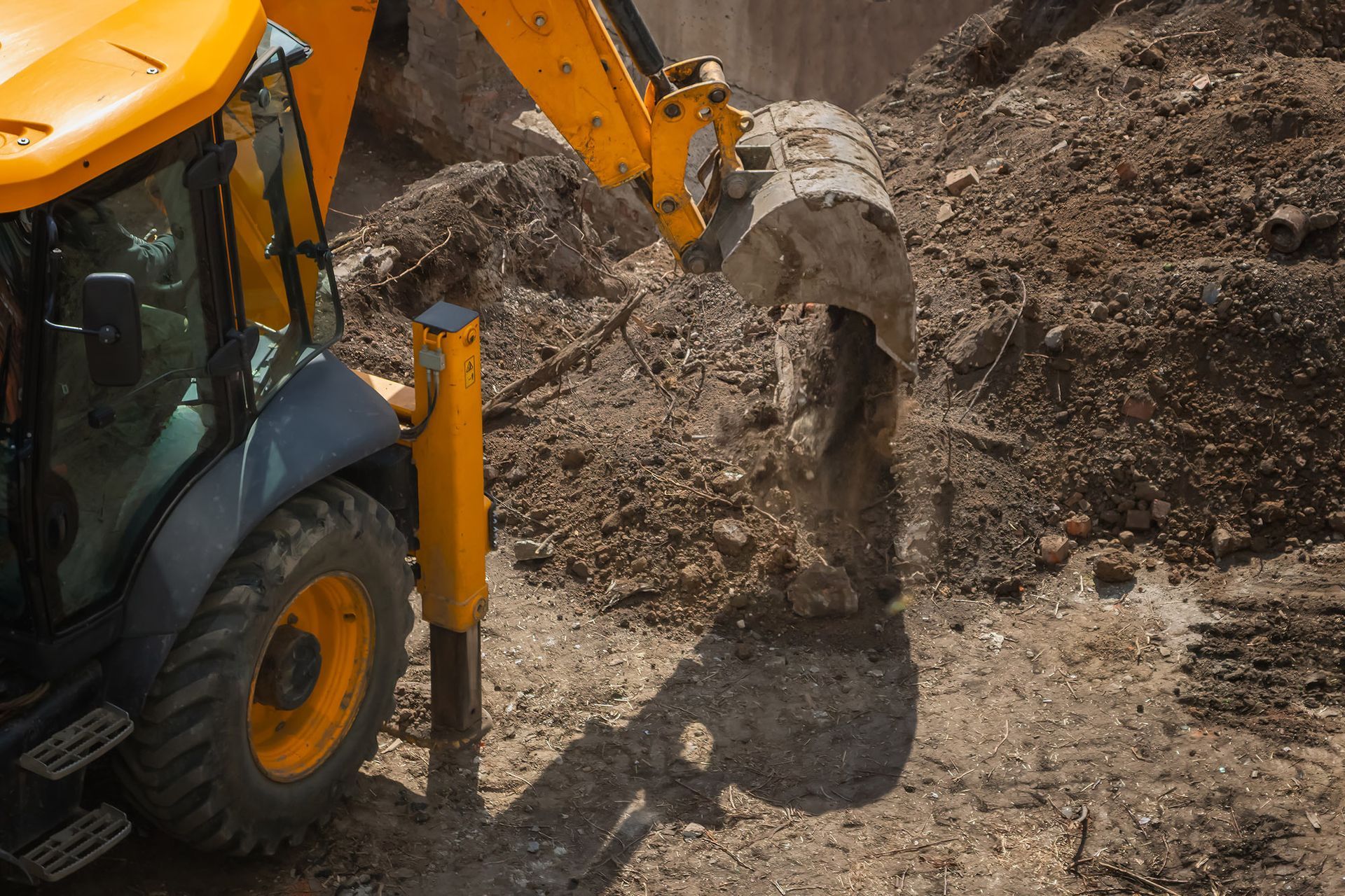Yellow backhoe digging in dirt.