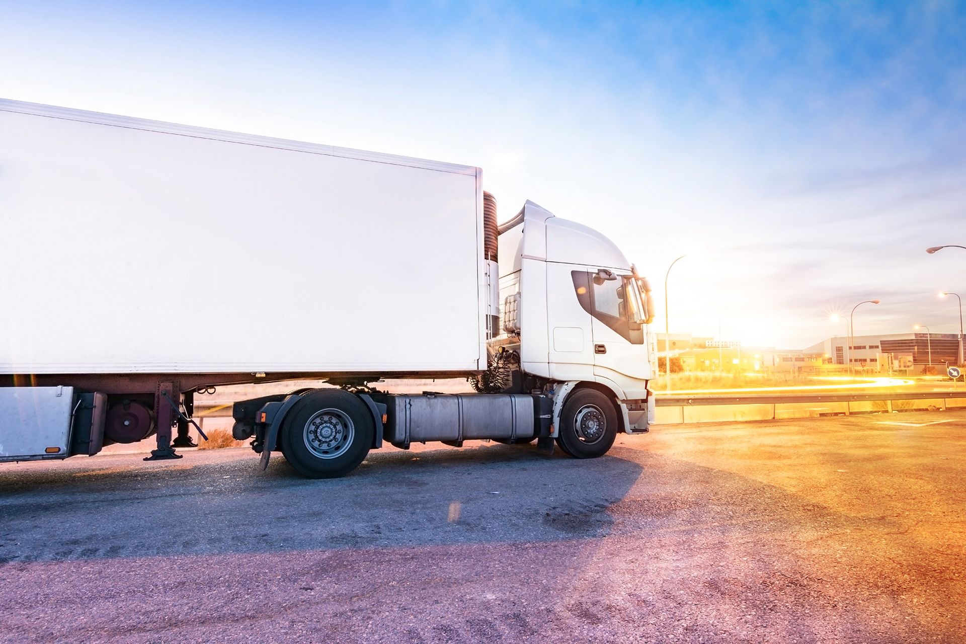 White semi-truck parked in a lot, sunny sky in the background.