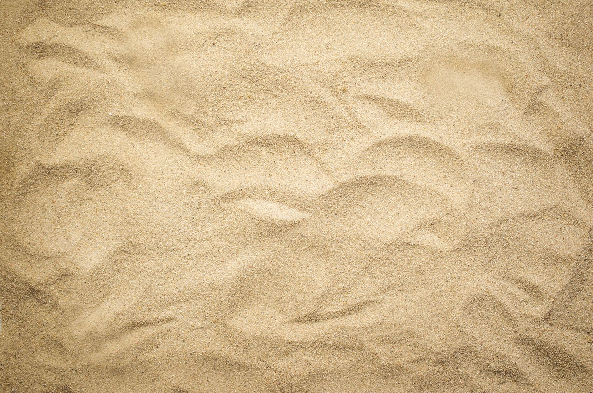 Sandy beach surface with rippled patterns, beige color.