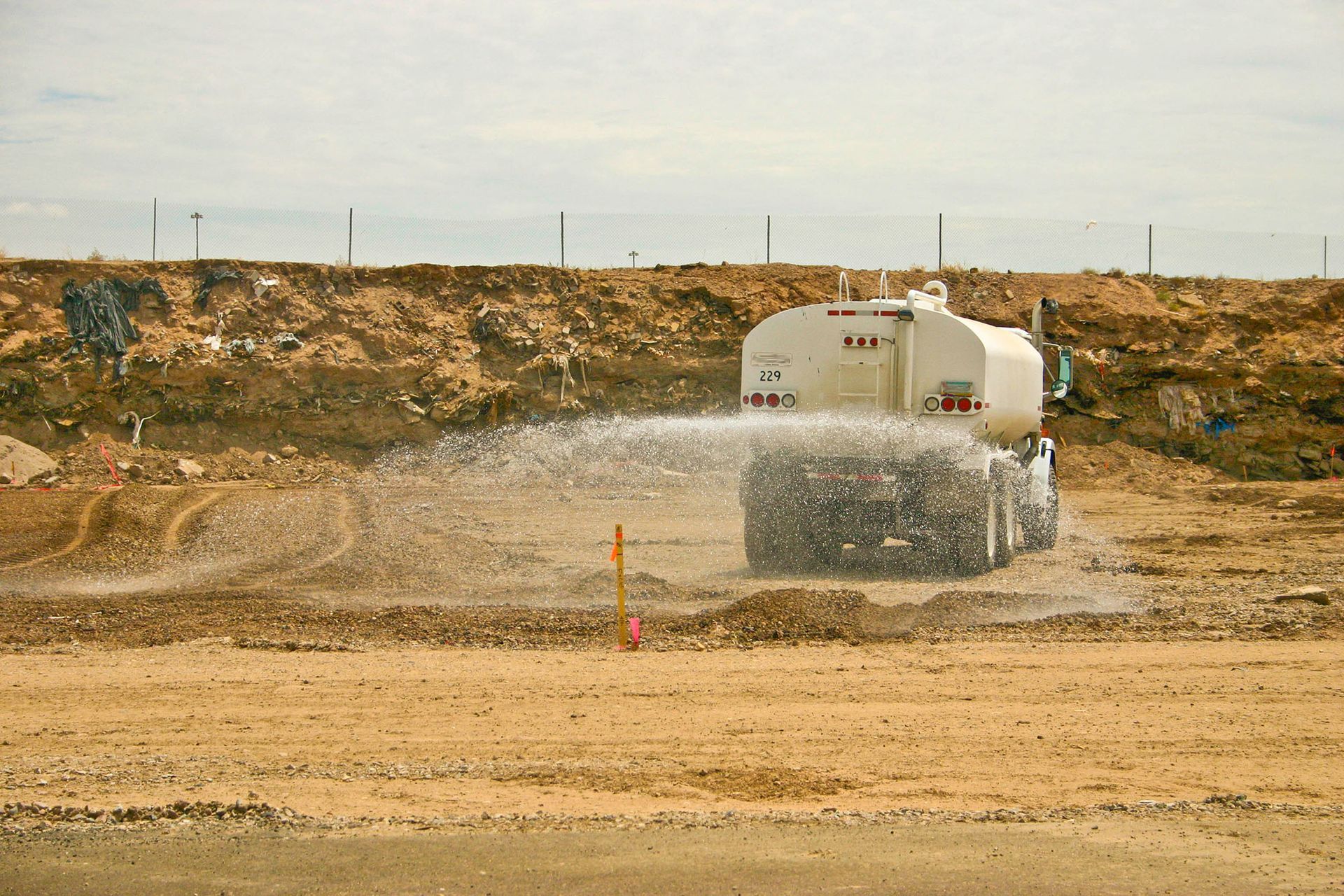 Water truck spraying water on dirt at a construction site to control dust.