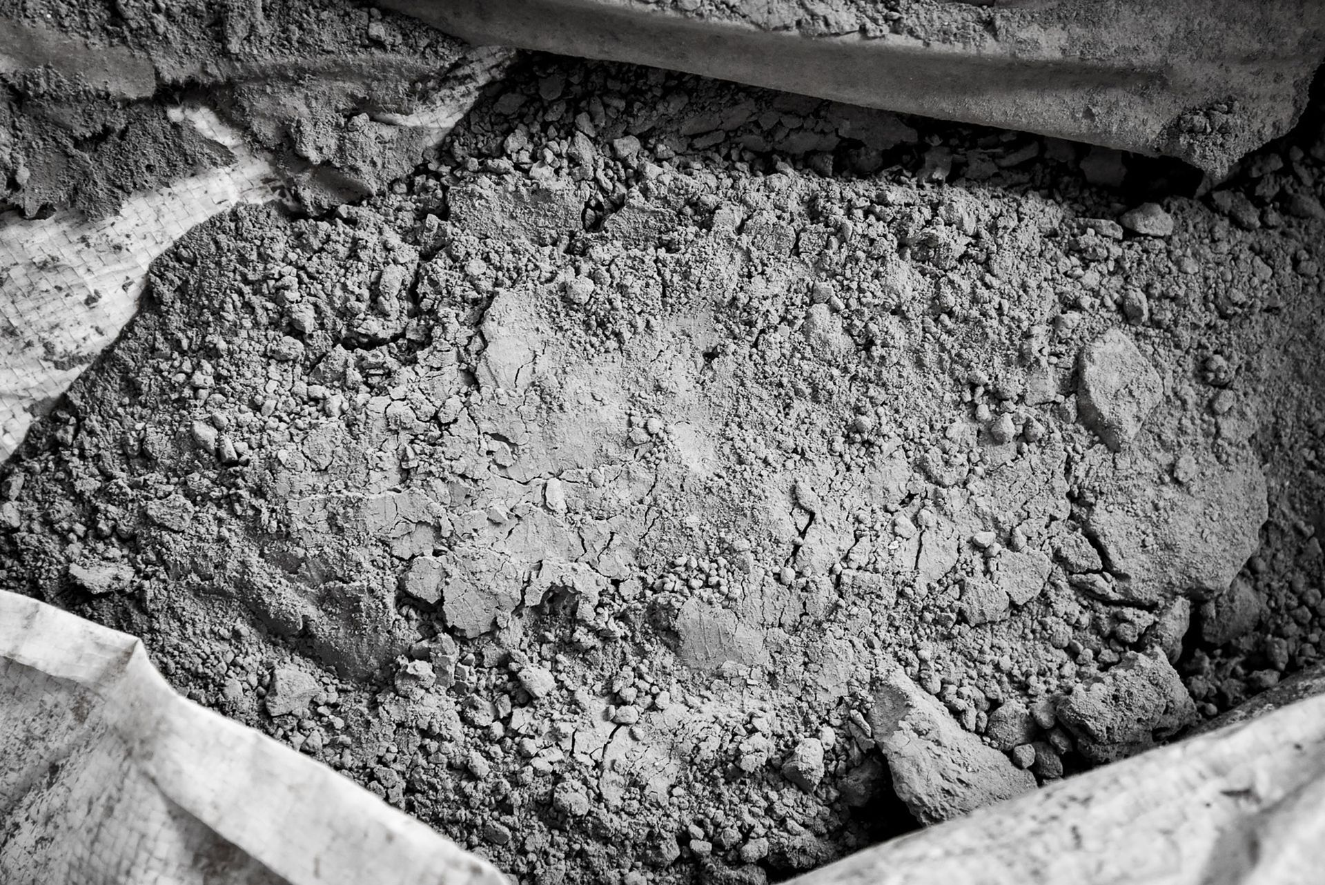 Gray, dusty cement mix inside a white bag, visible from an overhead angle.