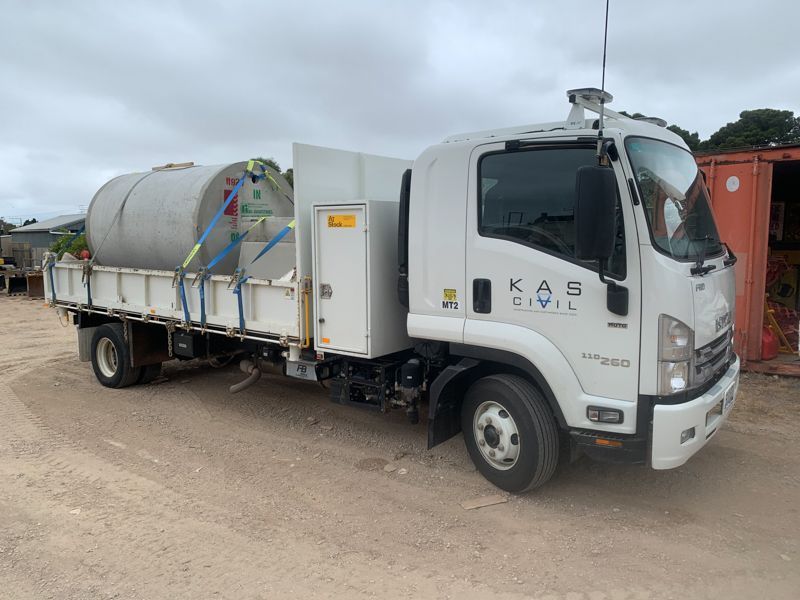 White KAS Civil truck with water tank on a dirt road.