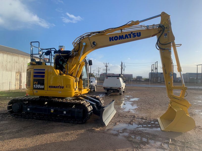 Yellow Komatsu excavator on a construction site; overcast sky.