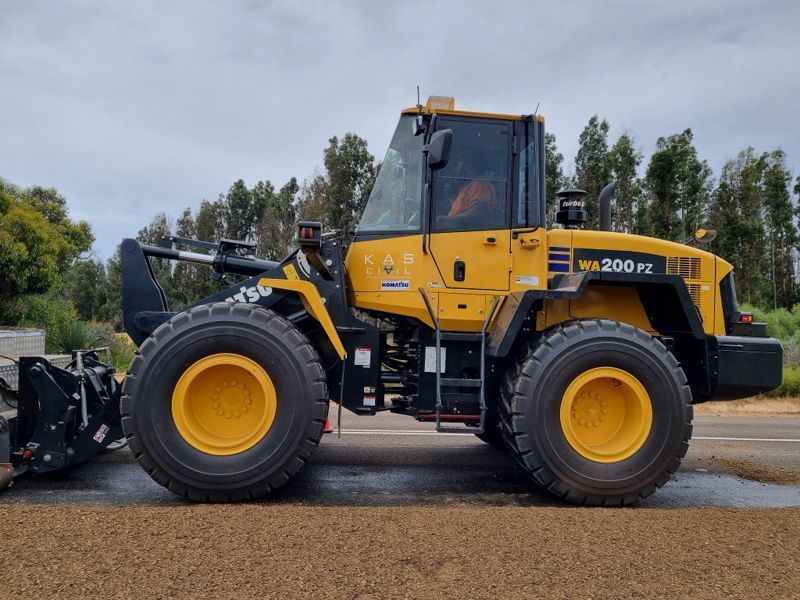 Yellow Komatsu WA200PZ wheel loader parked on asphalt.