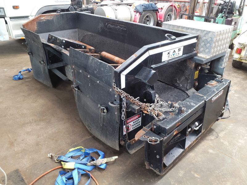 Black asphalt paving machine in a repair shop.