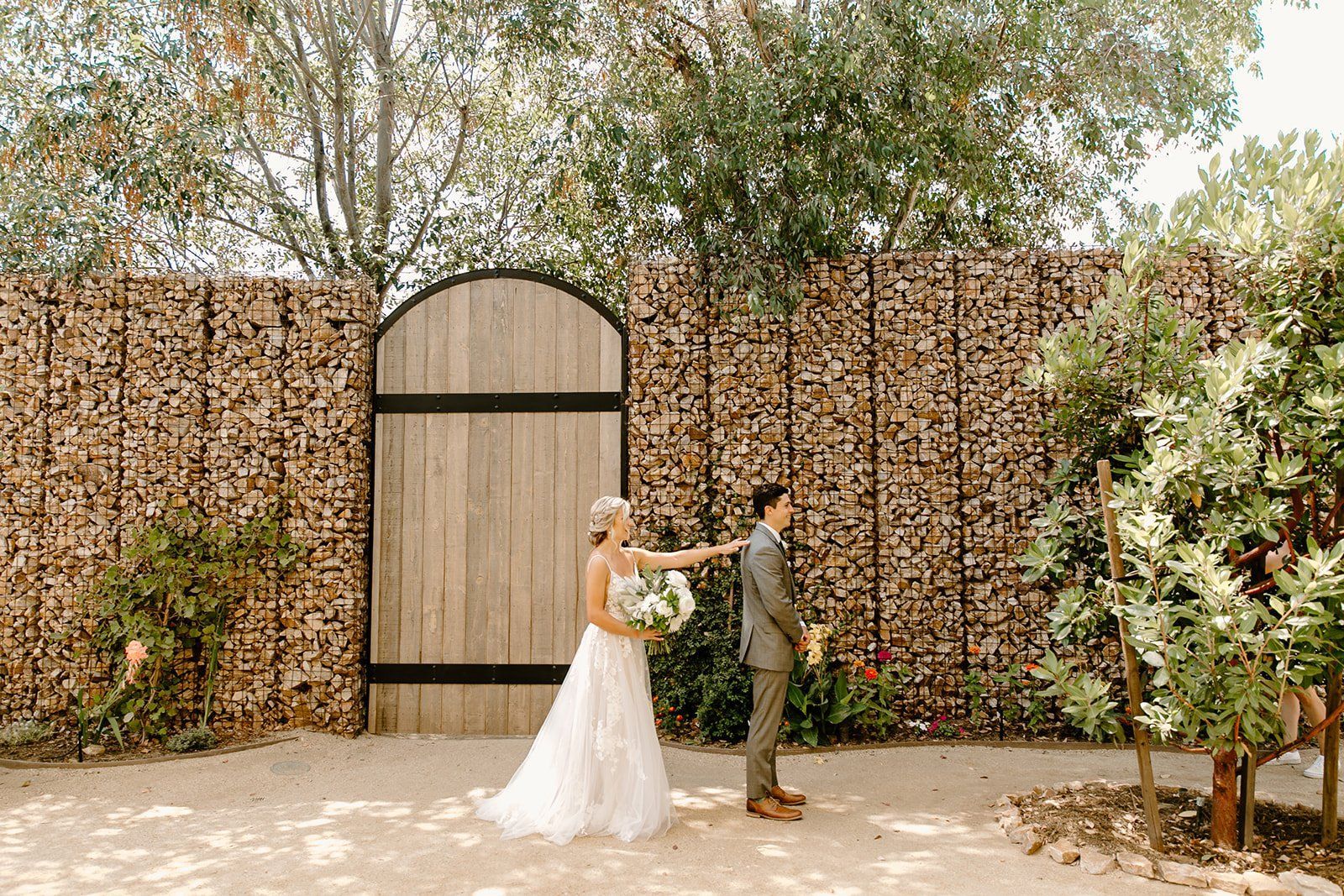 A bride and groom are standing in front of a wooden wall.