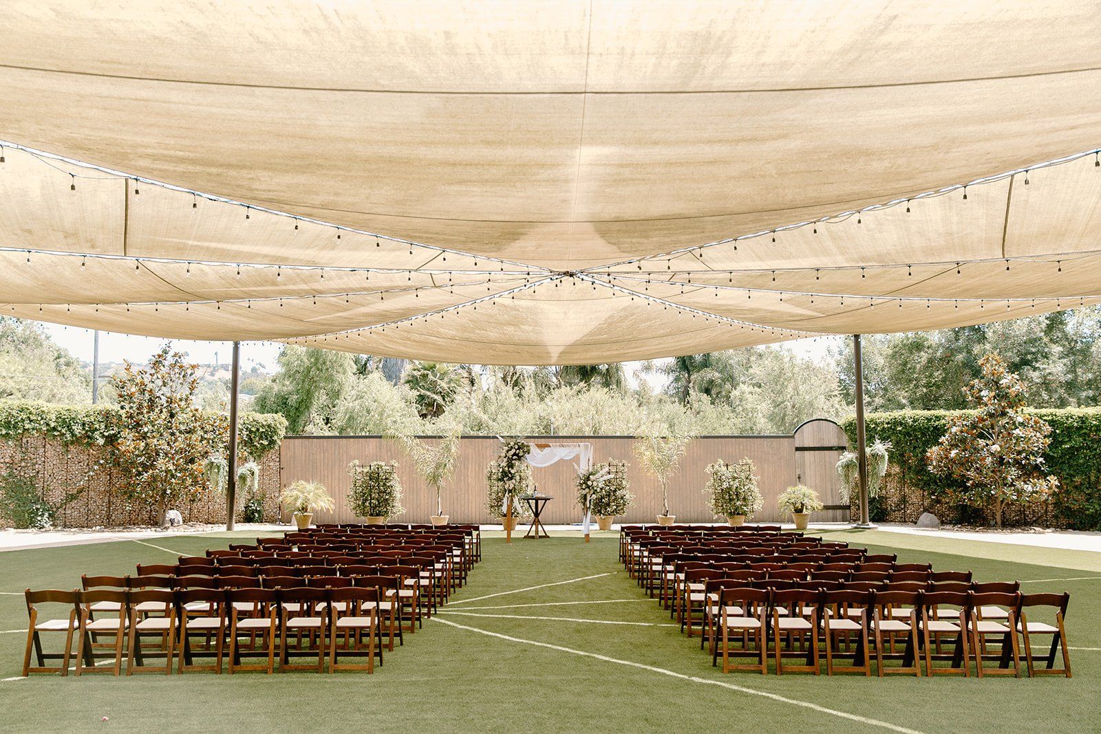 A row of chairs are lined up in a field under a canopy.