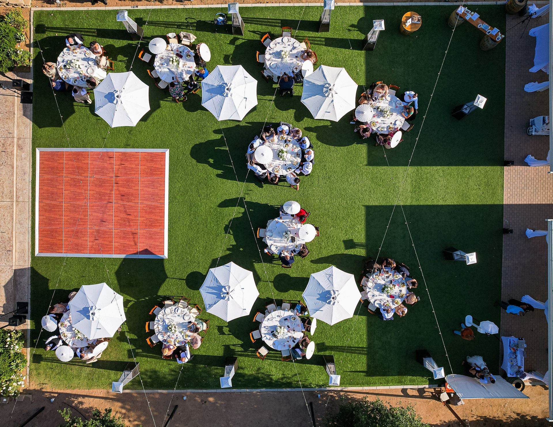 An aerial view of a lawn with tables and umbrellas and a dance floor