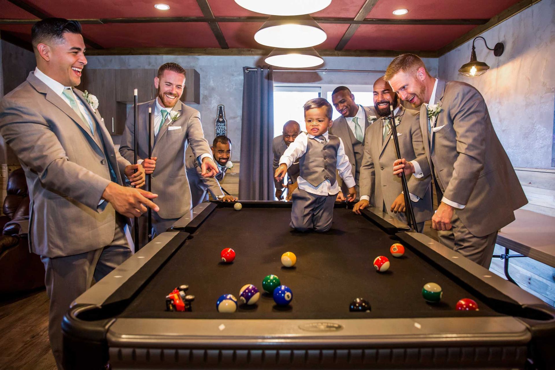 A group of men in suits are playing pool together.