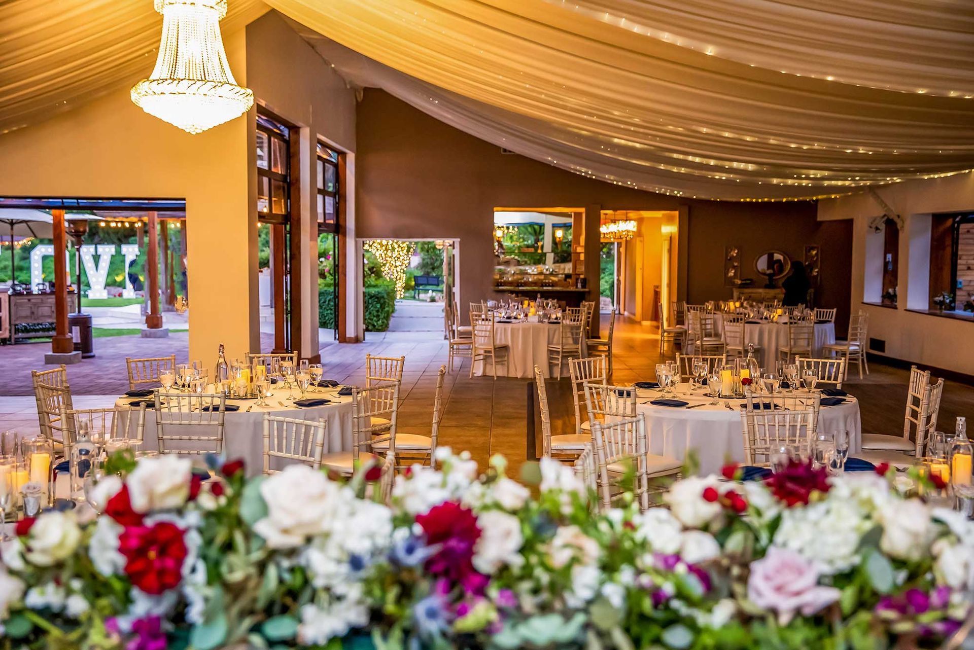 A large room with tables and chairs set up for a wedding reception.