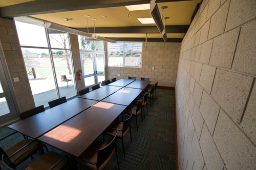 A long table and chairs in a room with a brick wall