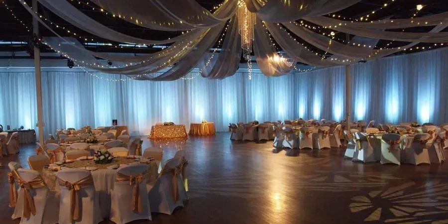 A large room with tables and chairs set up for a wedding reception.