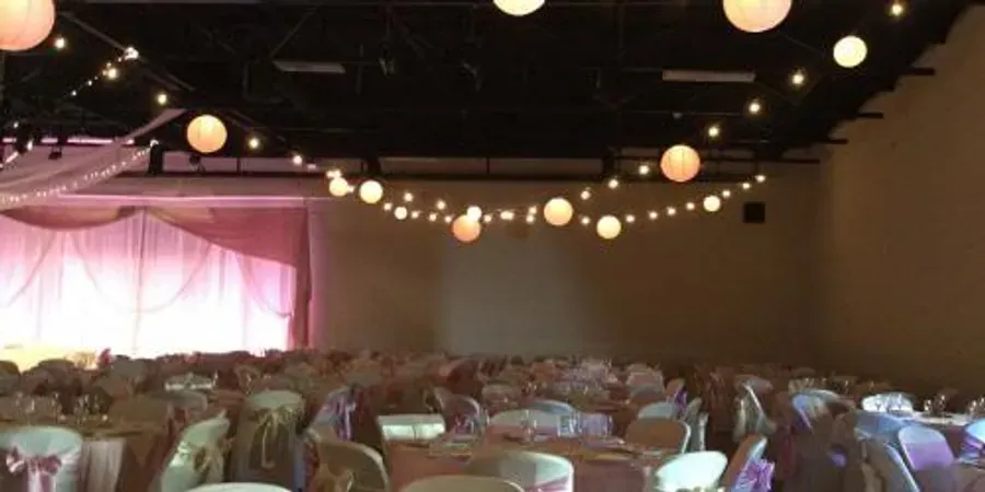A large room with tables and chairs set up for a wedding reception.