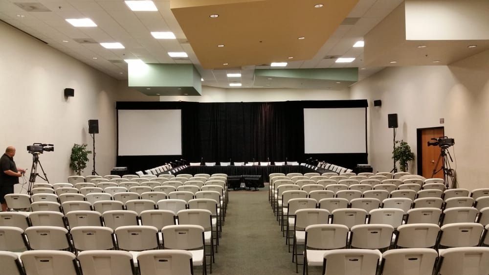 A large auditorium with rows of chairs and projector screens