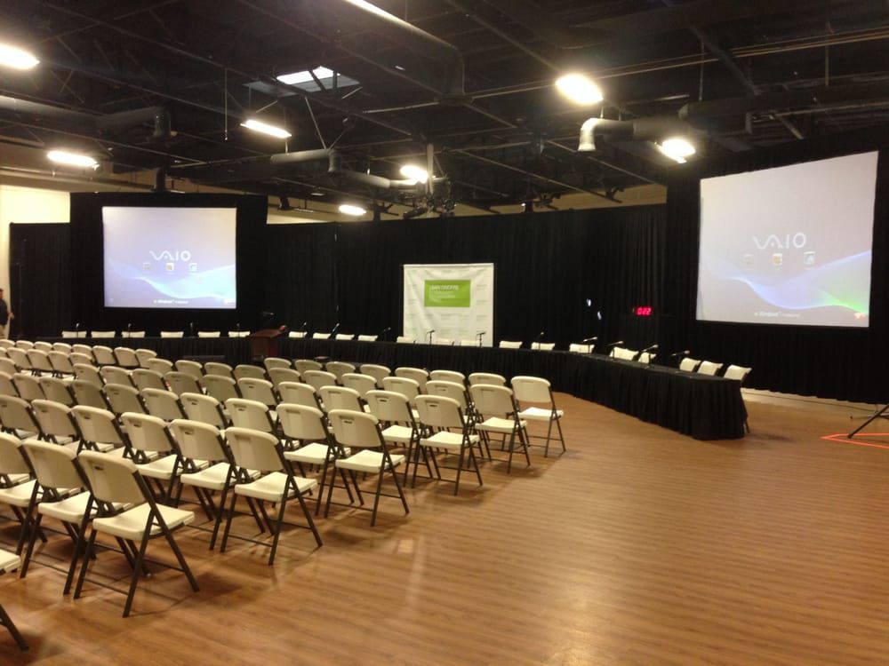 A large room with rows of chairs and projector screens that say vivo